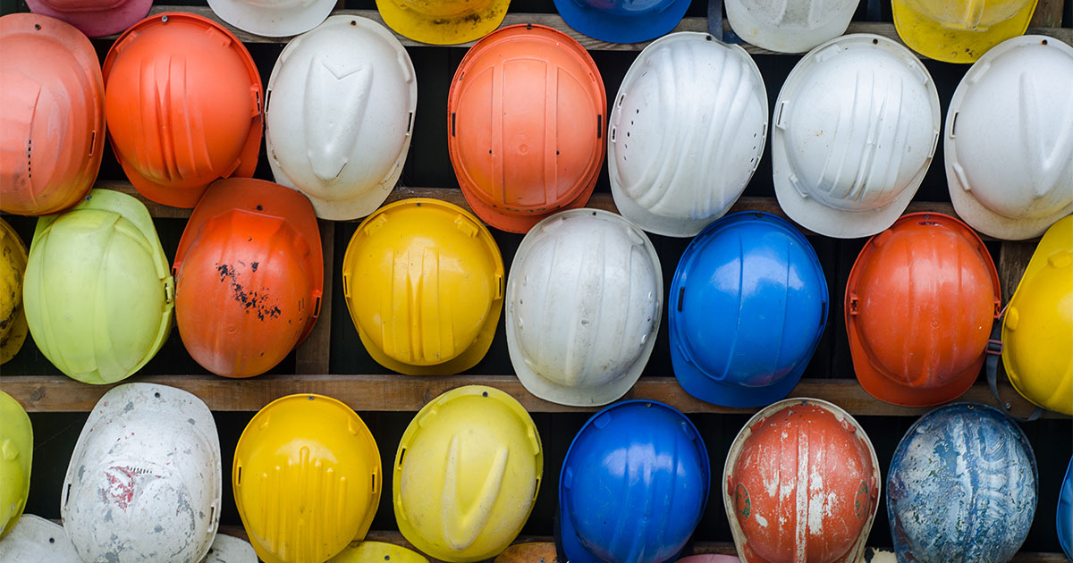 A variety of different hard hats that environmental consultants wear lined up in multiple rows