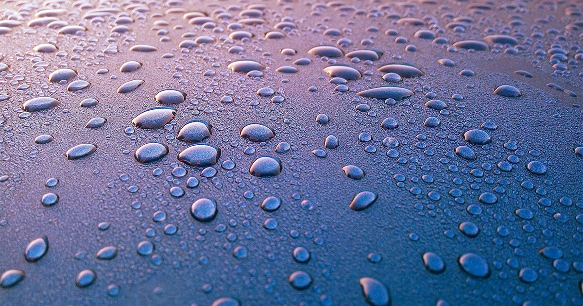 Water droplets pooling on blue surface treated with water resistant PFAS product
