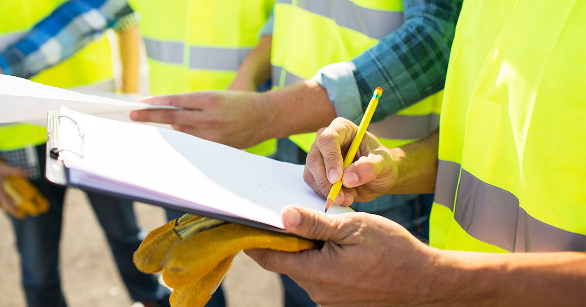 Environmental consultants in safety vests conducting real estate due diligence with clipboard