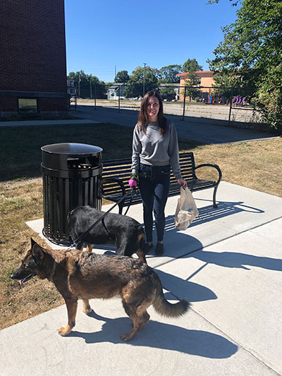 Dru holding trash and leashes of two dogs