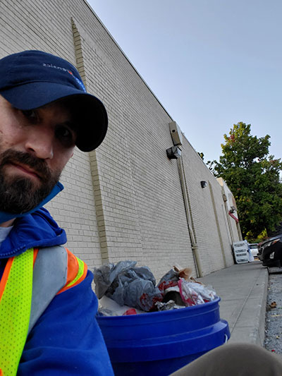 Nick Hill standing next to full garbage can