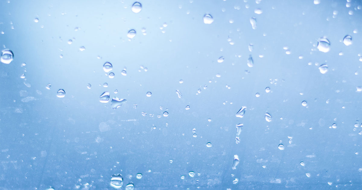 beads of water on PFAS treated glass in front of blue background