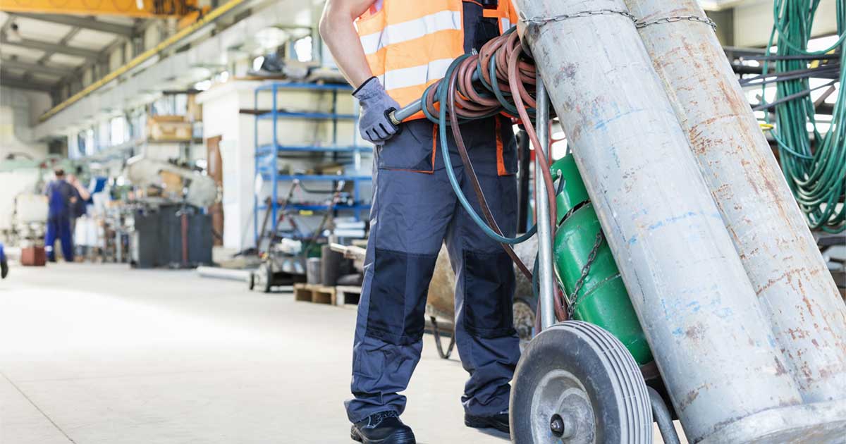 worker pushing drycleaner equipment on hand truck