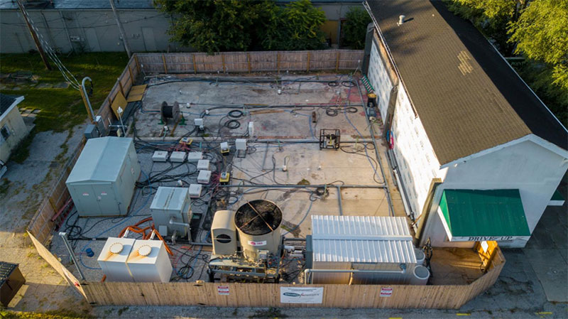 Aerial view of fenced in thermal remediation system behind an old drycleaning building