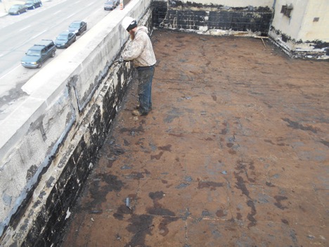 Construction worker removing built-up gravel from roof