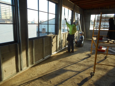 construction worker installing window in community room