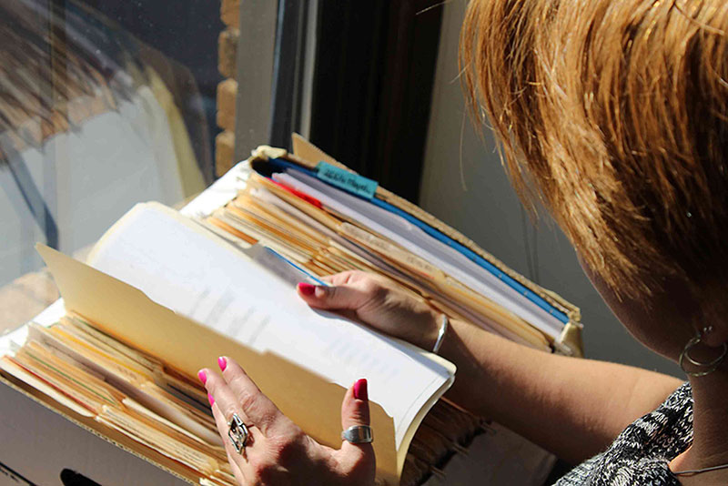 Insurance archeologist looking over old insurance files in front of sunlit window